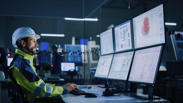 An industrial worker monitoring surveillance screens